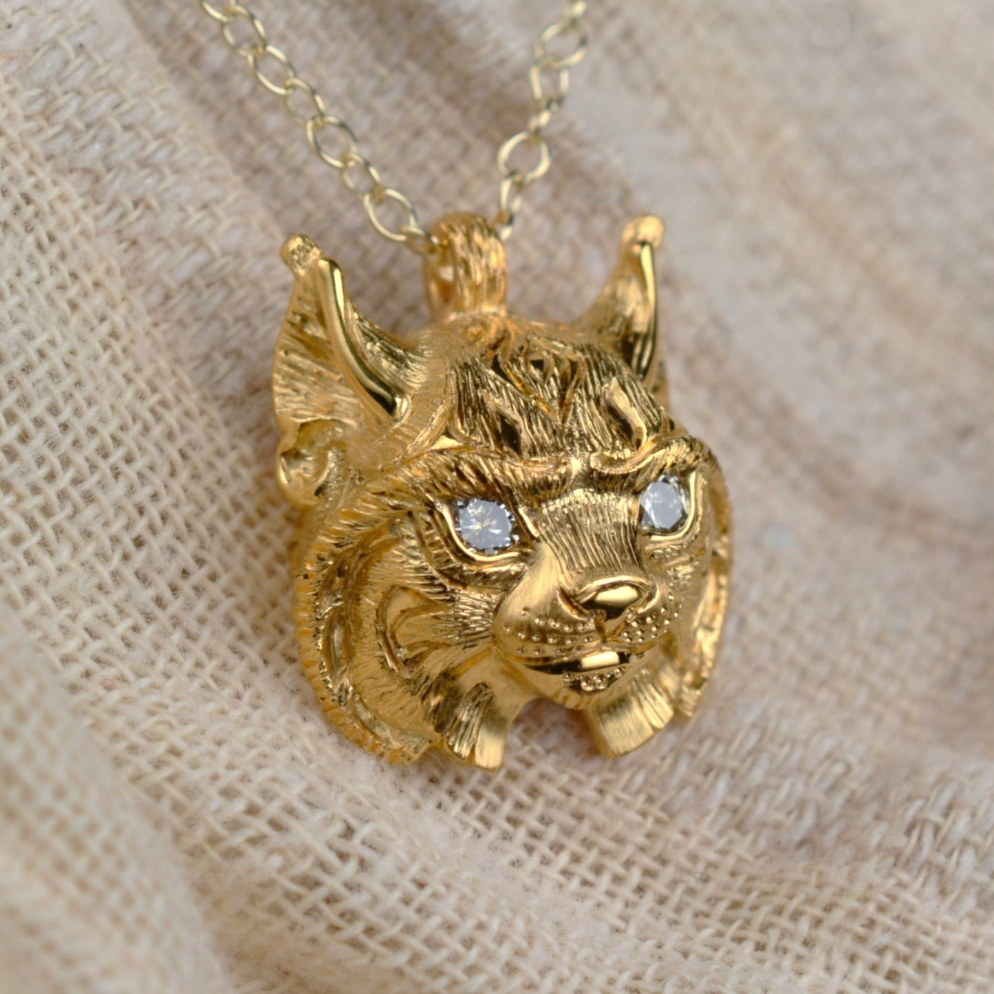 Gold lynx head pendant with diamond eyes and a gold chain.