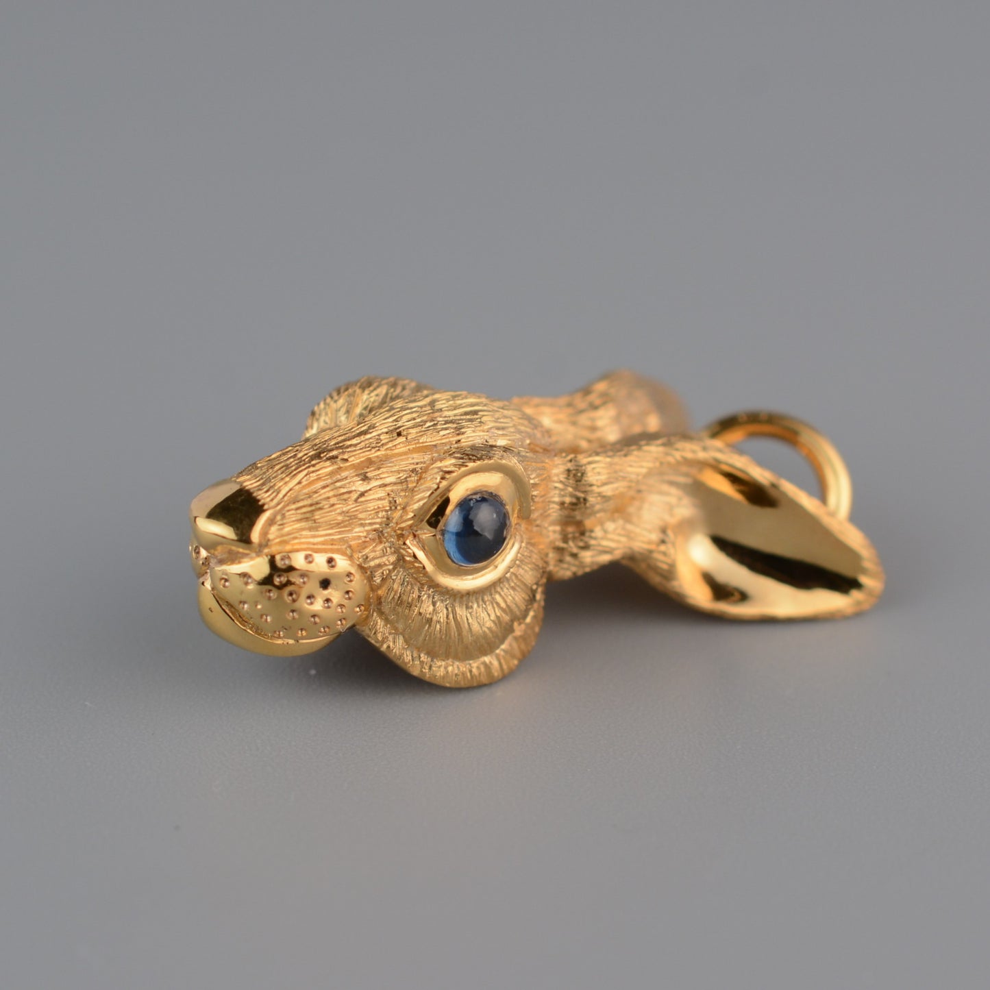 Gold rabbit necklace. Gold hare pendant with dark sapphire eyes and a gold chain. Hand made to order in the UK. © Adrian Ashley