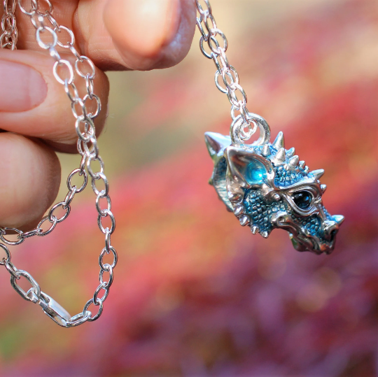 Silver dragon's head necklace. Sterling silver dragon pendant, with blue topaz eyes and a solid silver chain. Made to order. © Adrian Ashley