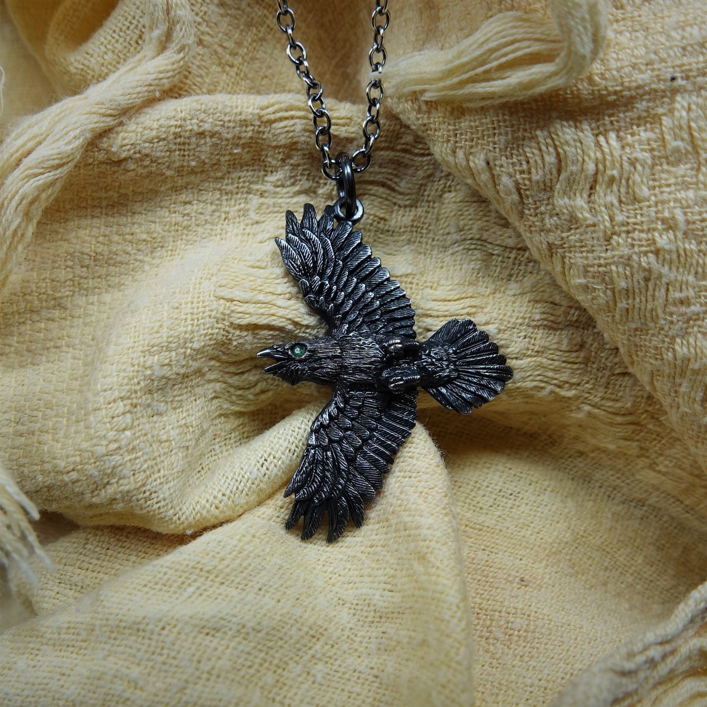 Raven necklace, double sided silver and emerald pendant with a black finish and a silver chain. © Adrian Ashley