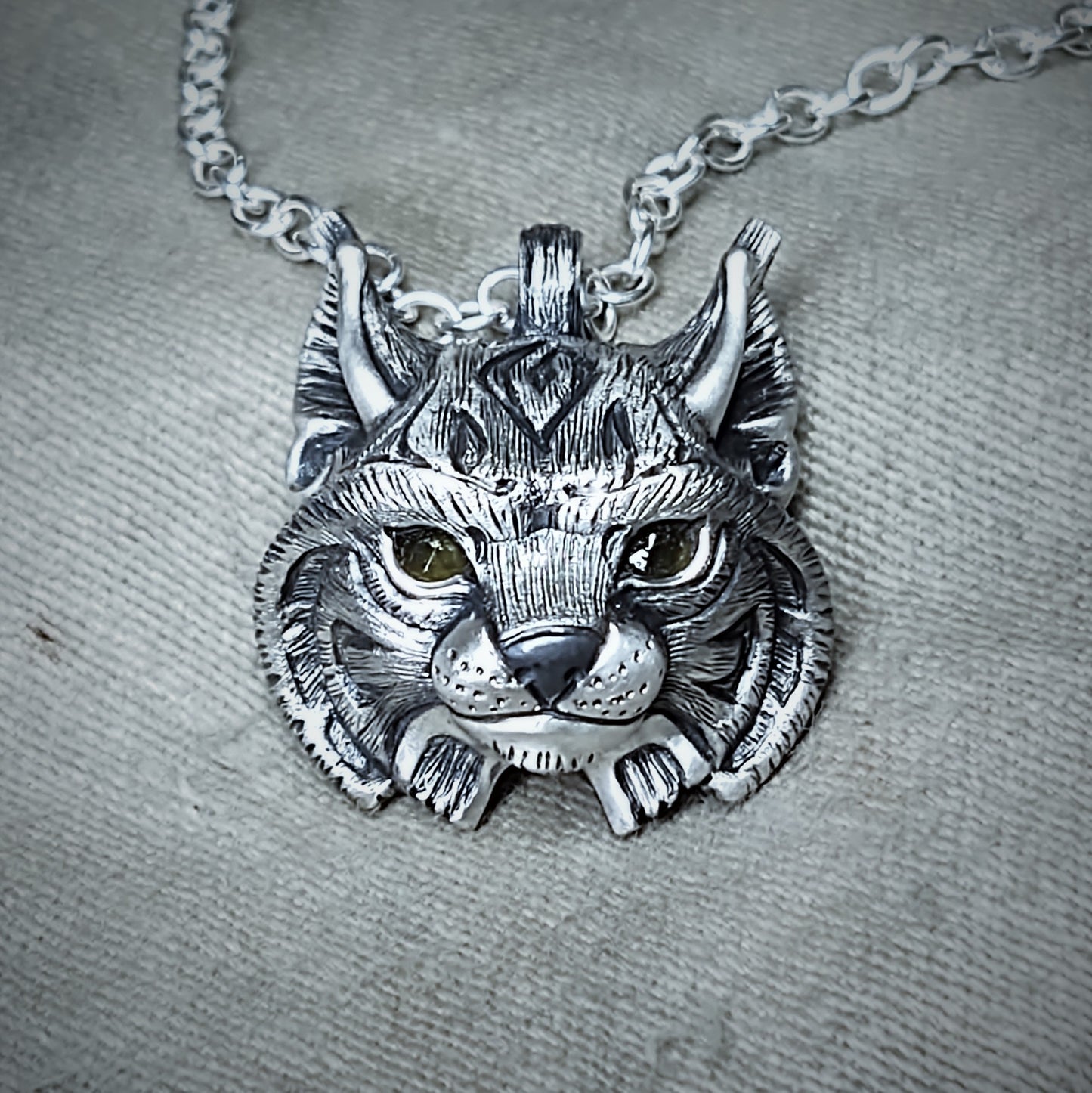 Mid-size Lynx Necklace. Sterling silver lynx's head pendant with natural gemstone eyes and a solid silver chain. Hand made to order. © Adrian Ashley