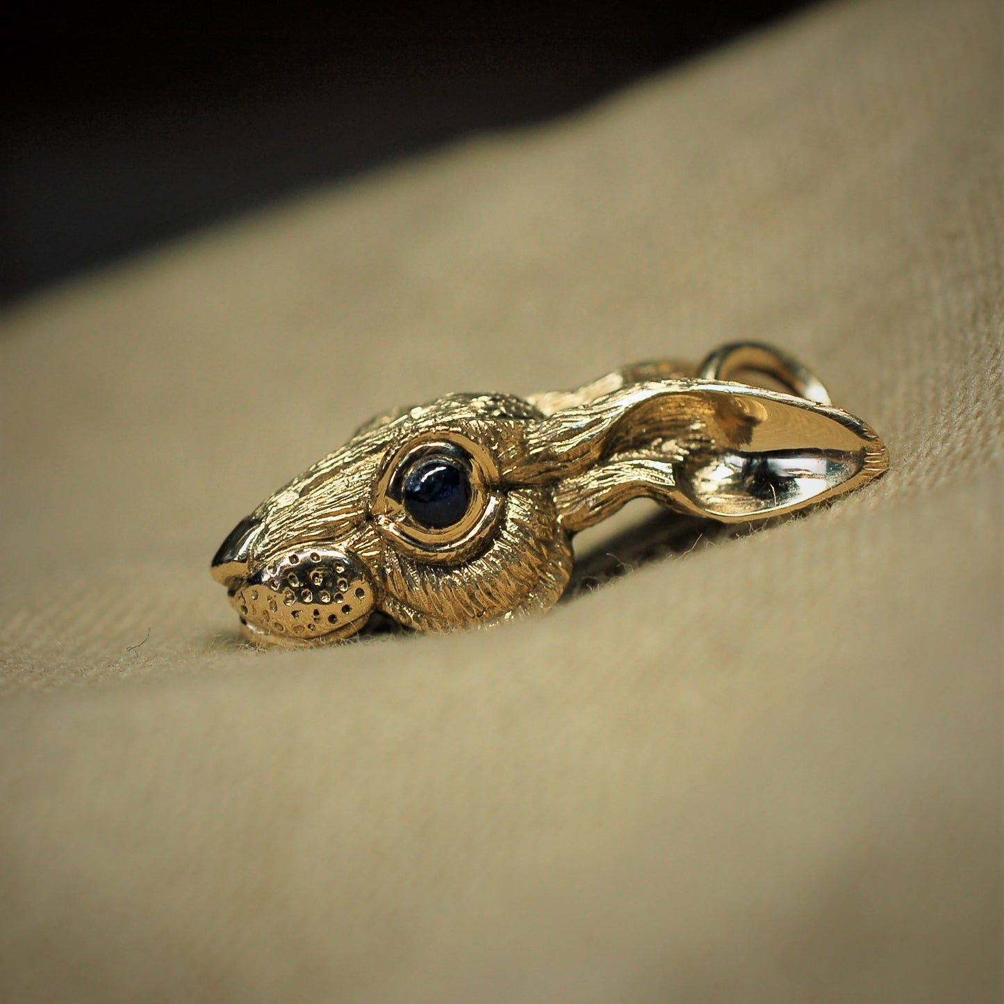 Gold rabbit necklace. Gold hare pendant with dark sapphire eyes and a gold chain. Hand made to order in the UK. © Adrian Ashley